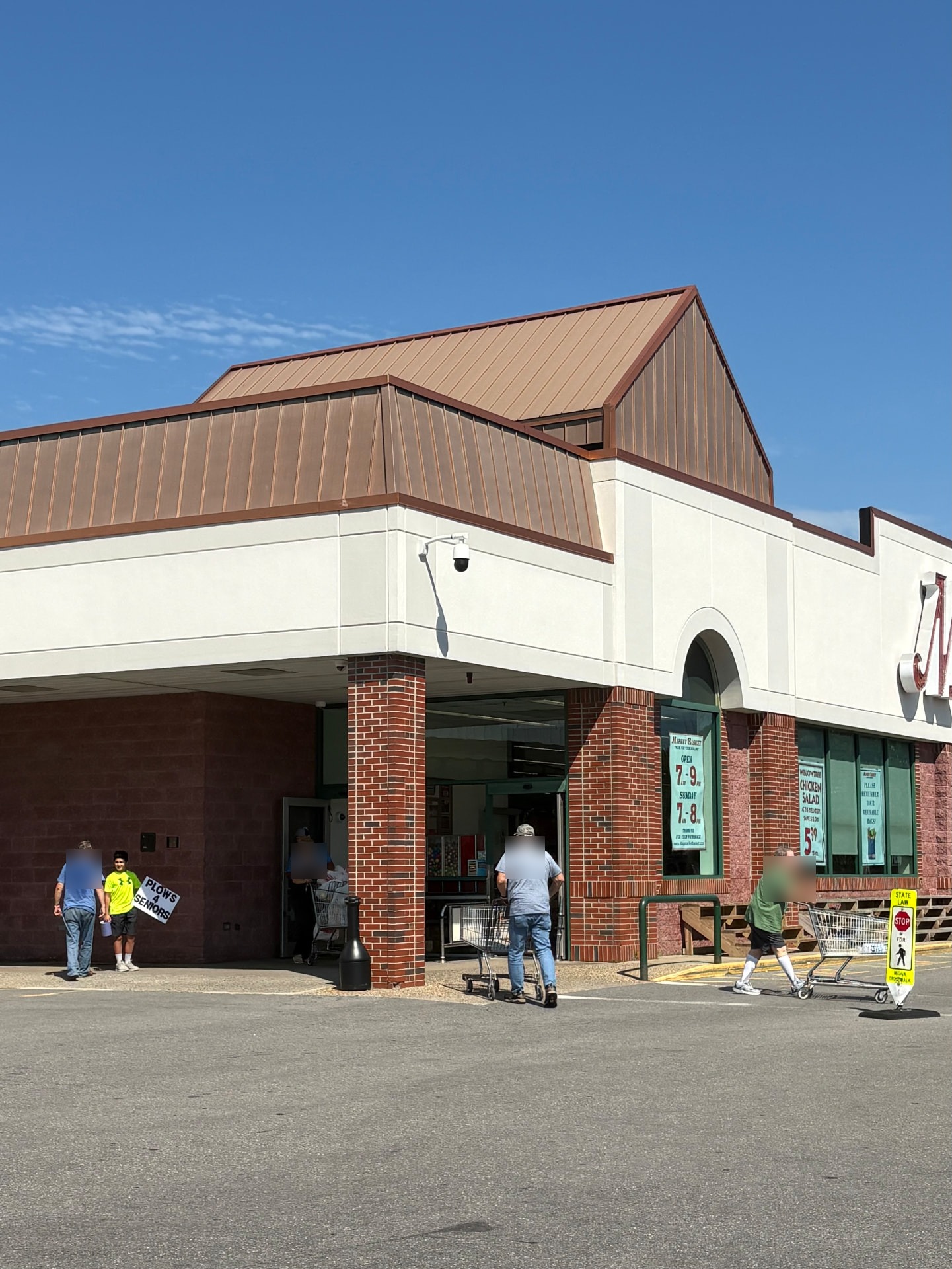 Plows4Seniors volunteer holding a sign outside a Market Basket storefront during Tag Day